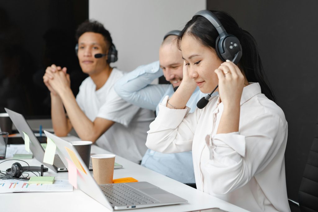 Diverse team of call center agents using laptops and headsets in a modern office setting.